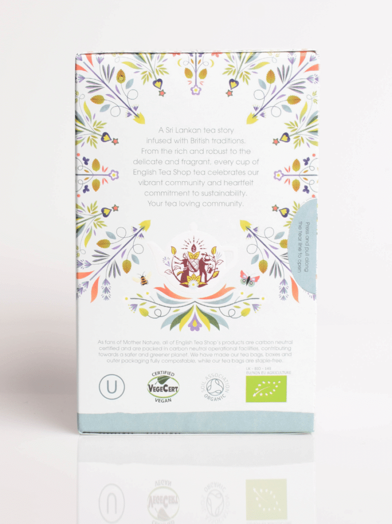 Bagpå teæske med farverigt blomstermønster, tekandeillustration og økologiske samt veganske certificeringslogoer