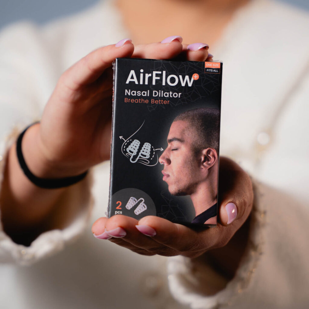 Hænder holder AirFlow næsedilatator-æske med mandprofil og produktillustration, 2 stk.